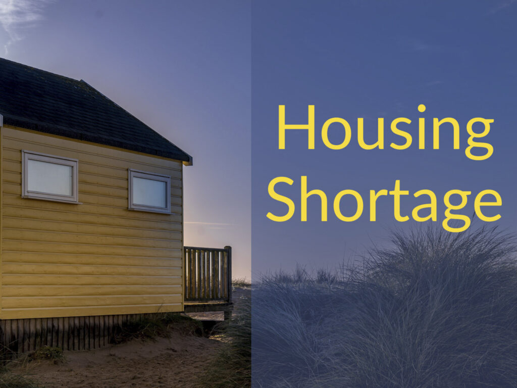 House on the beach at sunrise with caption "Housing Shortage"